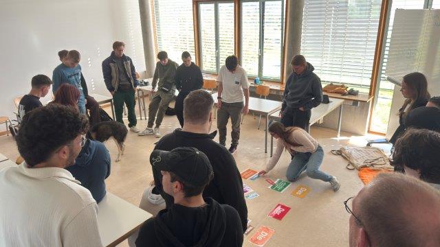 Schüler*innen in der Klasse; eine setzt Satzteile auf dem Boden zusammen