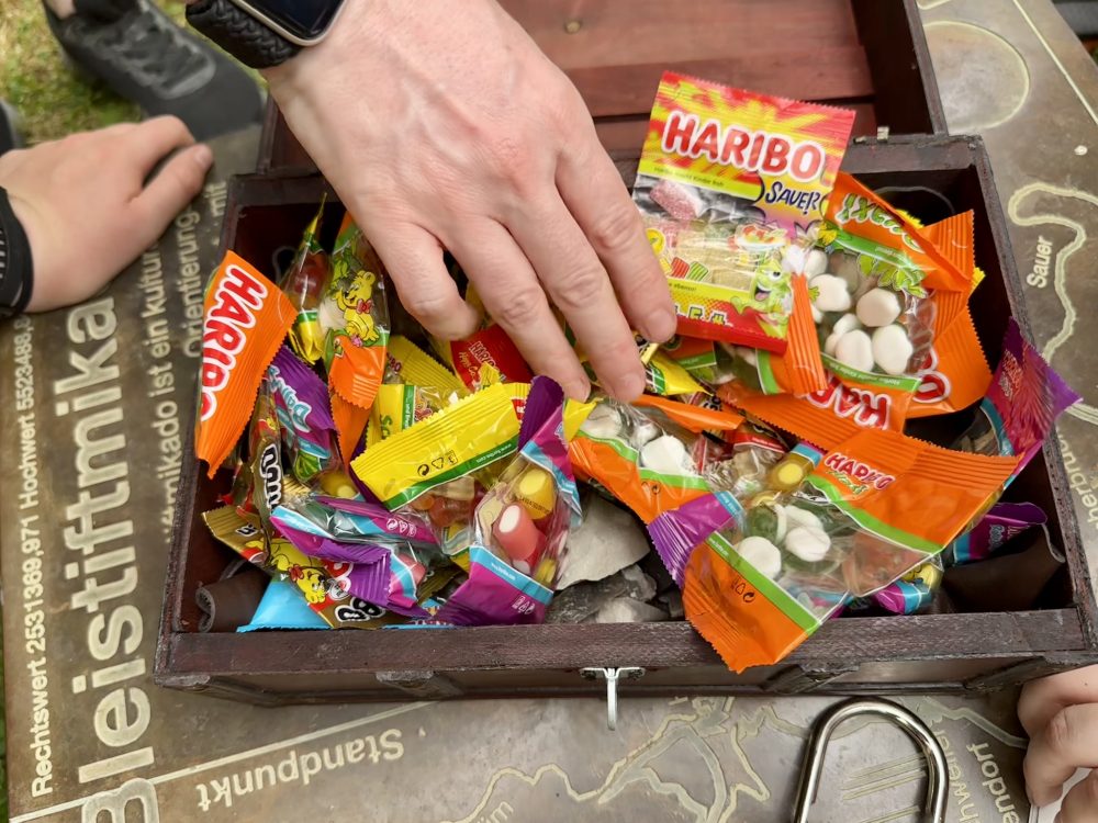 Man sieht eine Hand, die in eine Kiste mit Gummibärchen greift