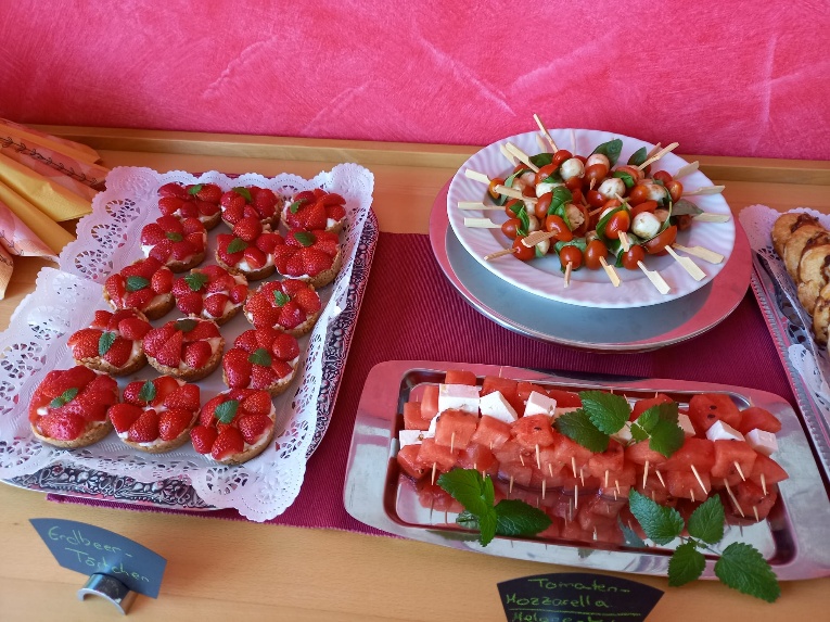 Auf dem Foto sind Erdbeer-Törtchen, Melone-Feta-Sticks und Tomate-Mozzarella-Sticks angerichtet