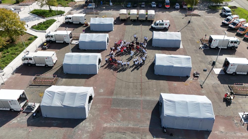 Sammelplatz mit Zelten und Personen in einem großen Kreis