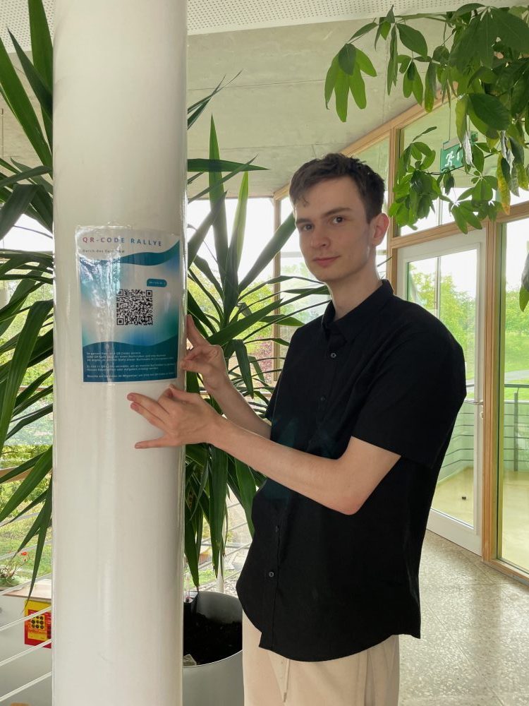 Ein Auszubildender befestigt QR-Codes für die Rallye