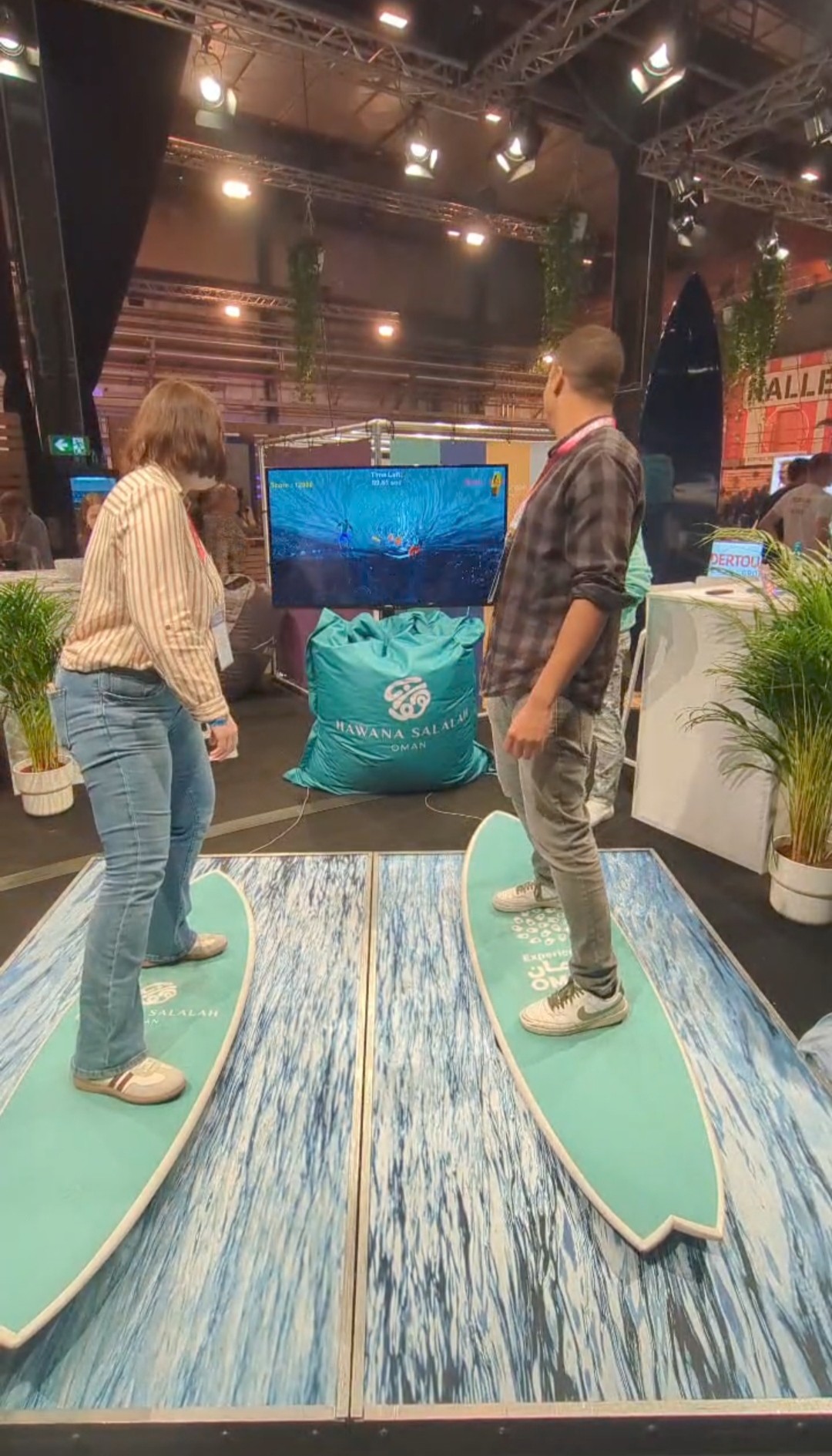 Zwei Auszubildende "surfen" auf Surfbrettern vor einem Bildschirm