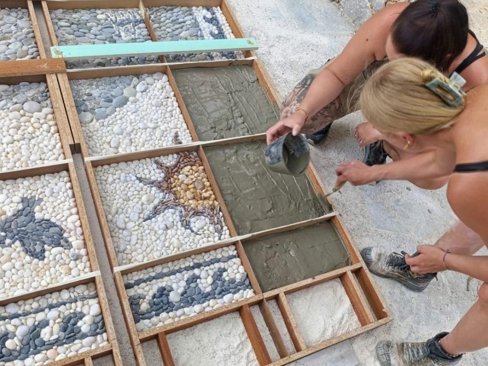 Zwei Personen arbeiten an dem großen Wandmosaik