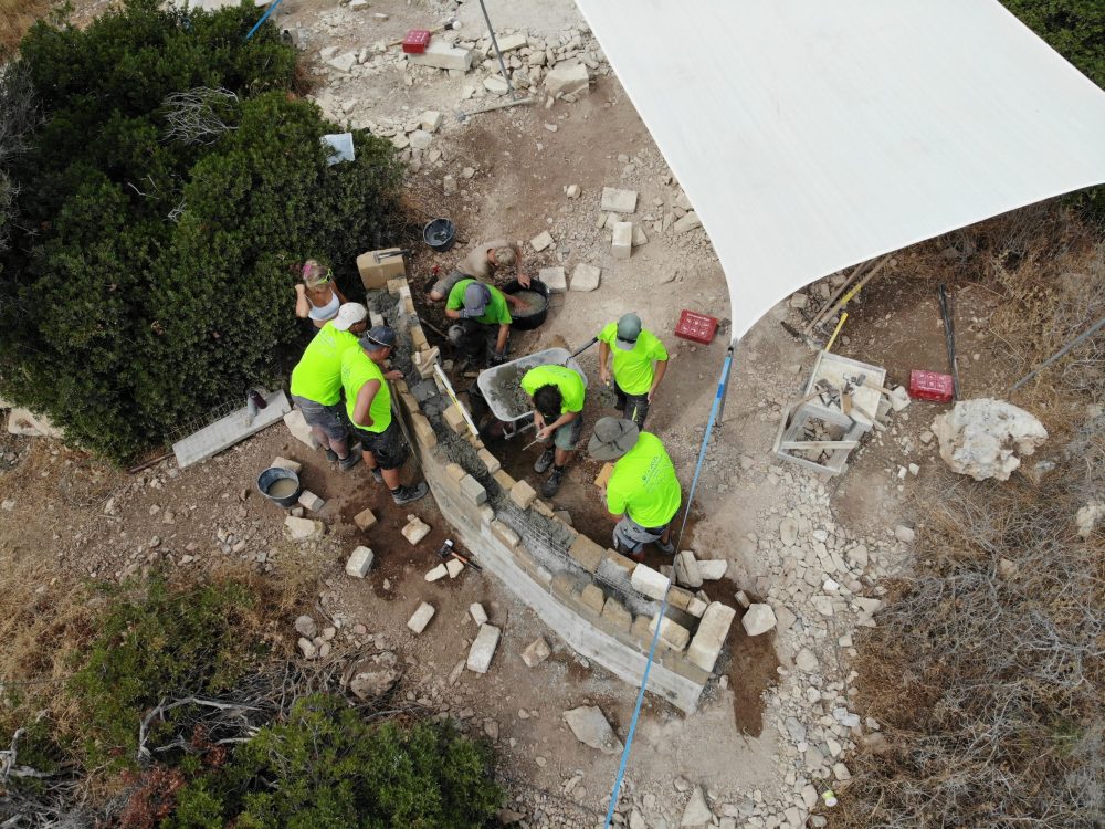 Sechs Personen bauen eine Mauer unter einem Sonnensegel