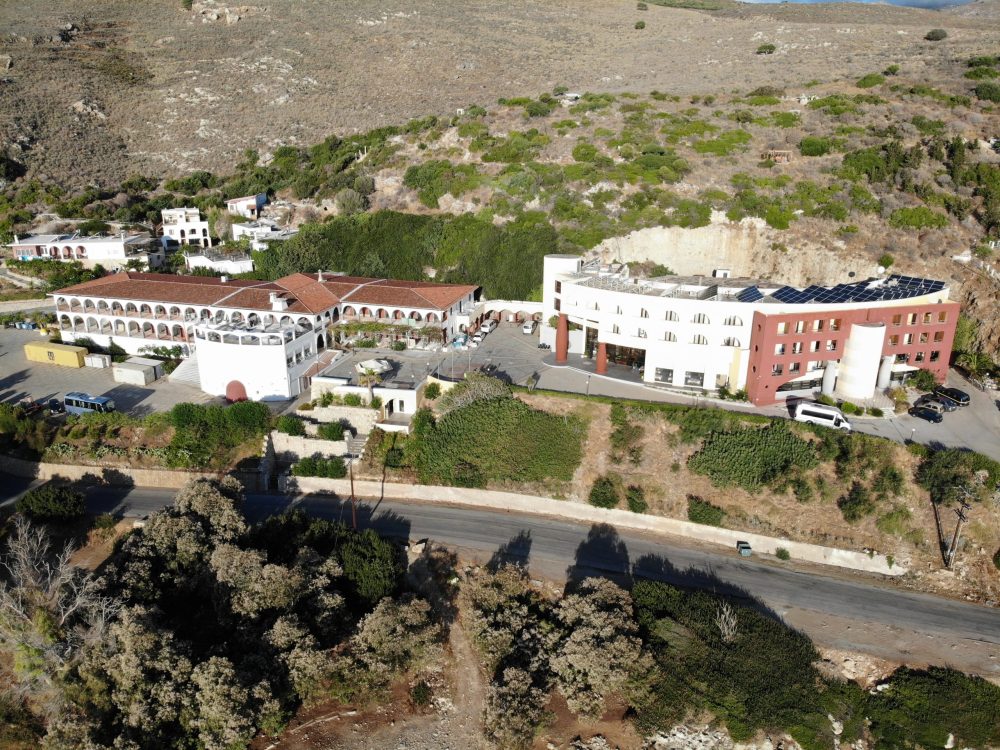 Man sieht die Orthodoxe Akademie Kreta und eine Straße von oben