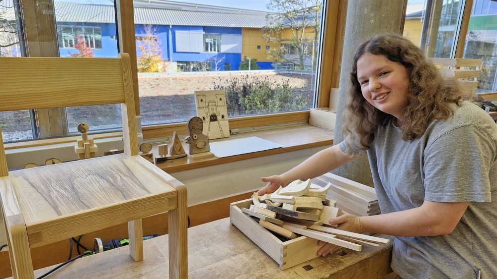 Lina Nels zeigt eine Kiste mit verschiedenen Holzprodukten