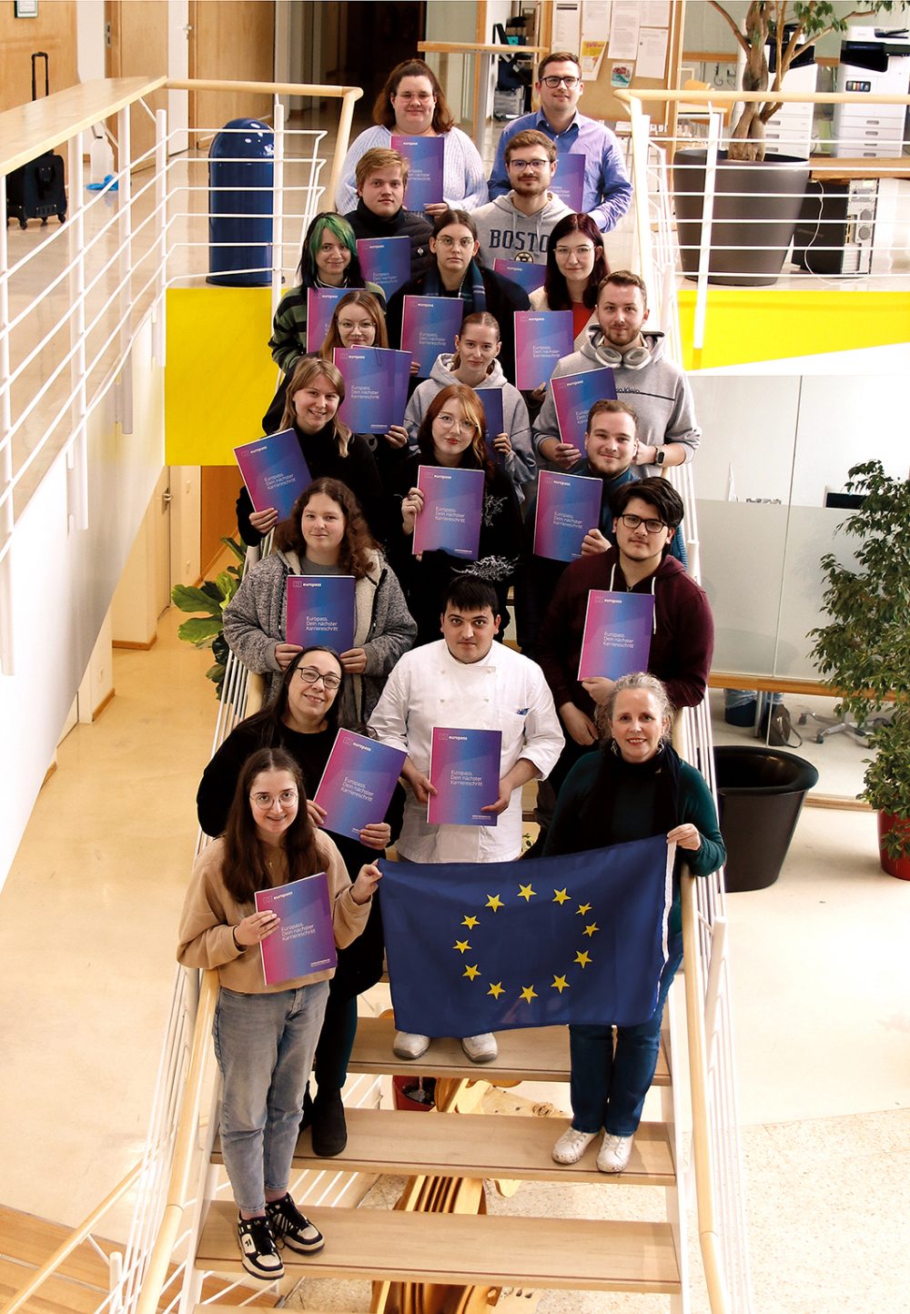 Insgesamt 19 Personen mit ihren Europässen und der EU-Flagge im Vordergrund