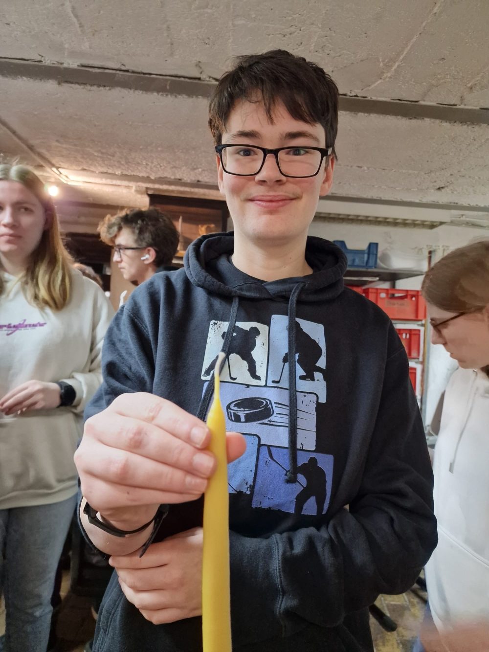 Eine Auszubildende hält eine fertige Bienenwachskerze in die Kamera