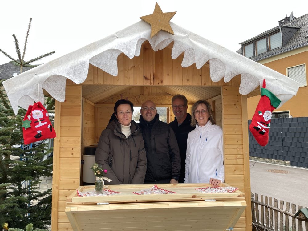 Vier Personen in einer weihnachtlich geschmückten Holzbude