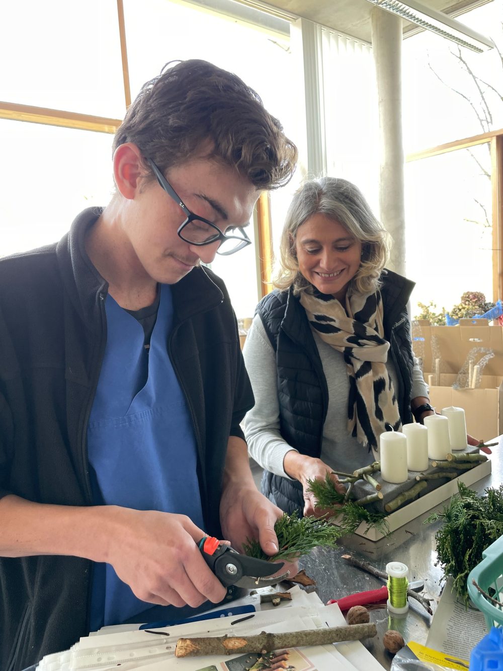 Ein Auszubildender und eine Ausbilderin beim Erstellen der Adventsgestecke