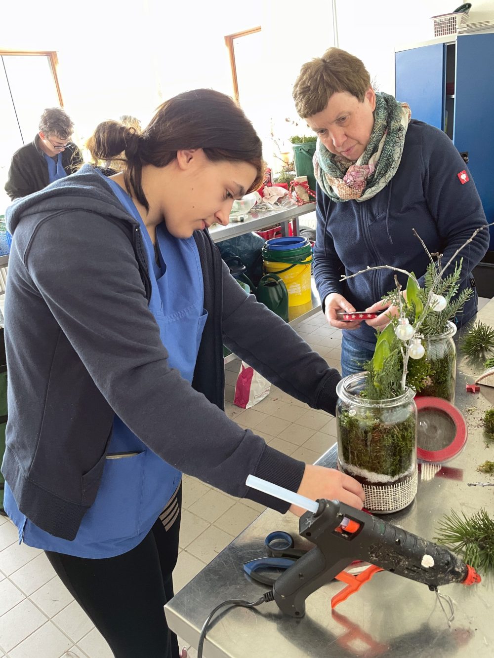 Eine Auszubildende und eine Ausbilderin beim erstellen der Adventsgestecke