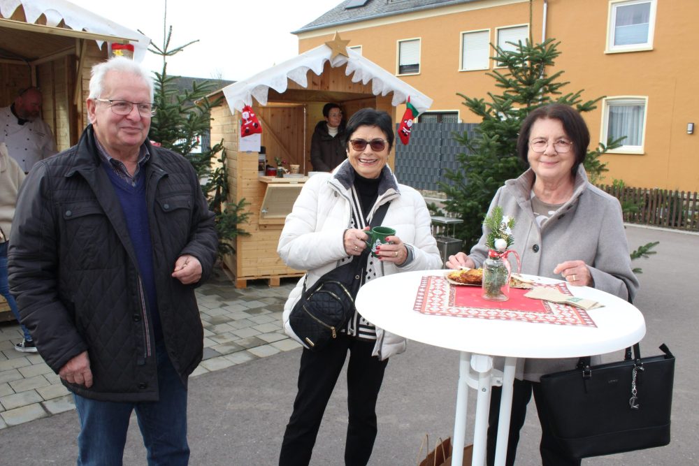 Eine Gruppe mit drei Personen vor einer Verkaufsbude