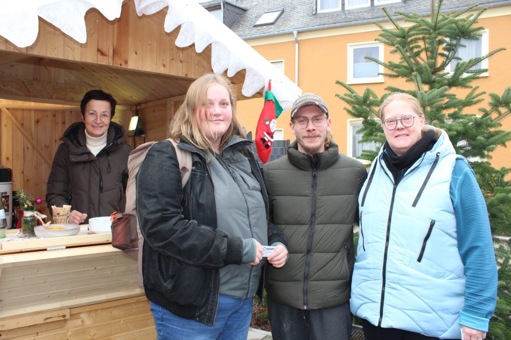 Drei Personen vor, eine in einer Verkaufsbude