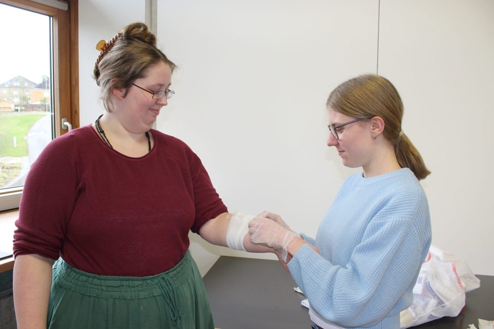 zwei junge Frauen üben, wie man Verbände anlegt
