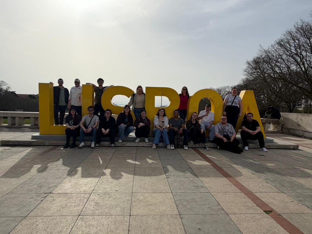 Gruppenfoto mit allen Auszubildenden und Betreuer*innen vor und zwischen dem Schriftzug "Lisboa"