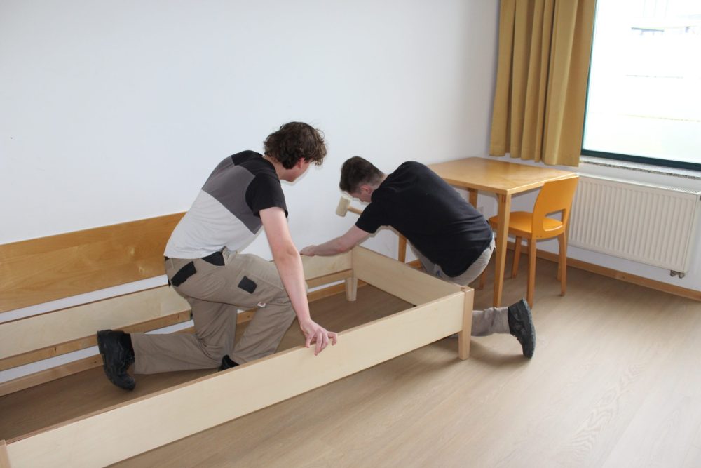 zwei Auszubildende bearbeiten einen Bettrahmen