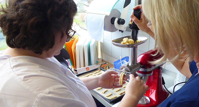 eine Auszubildende und eine Ausbilderin erstellen Spritzgebäck an einem Teigwolf