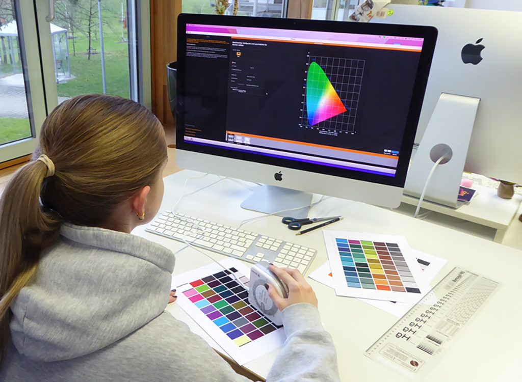 man sieht eine junge Frau vor einem Bildschirm bei der Farbauswahl