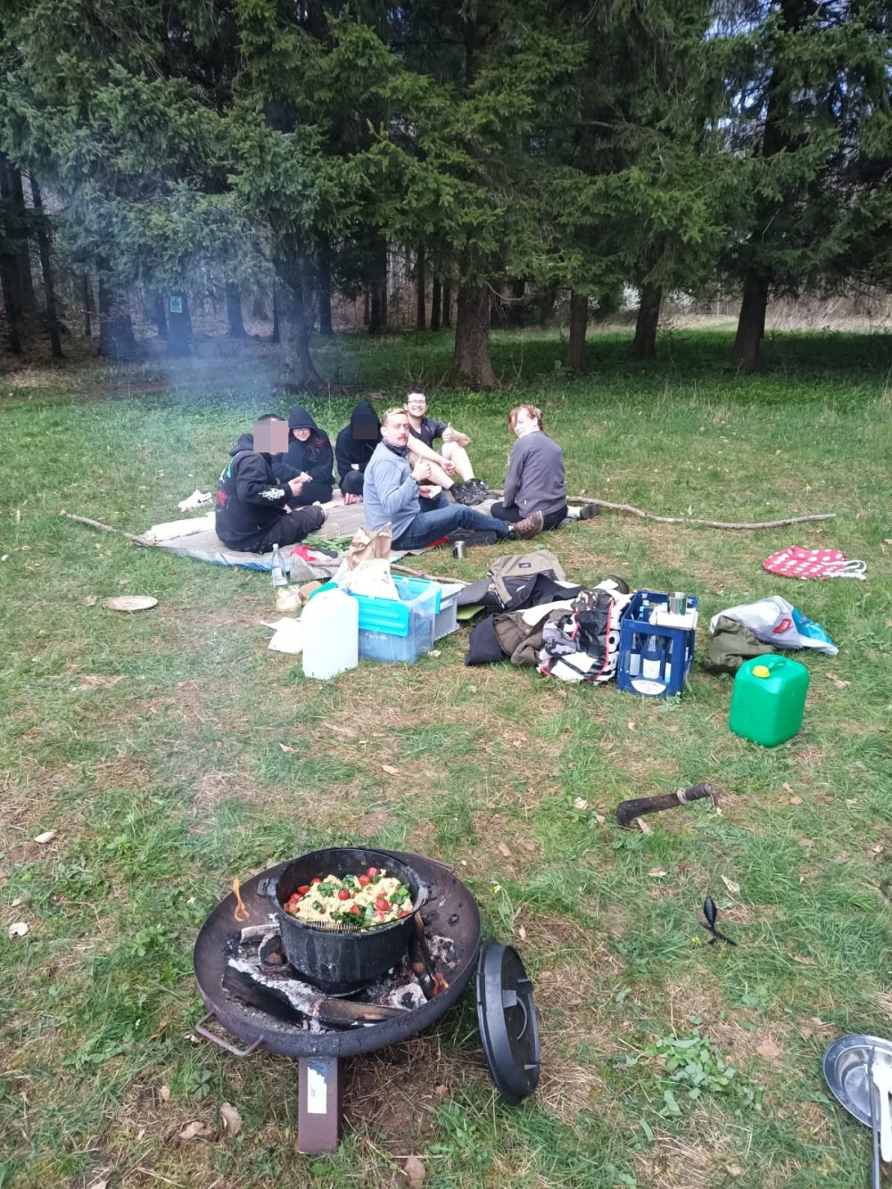 eine Gruppe Teilnehmende sitzt auf einer Picknickdecke im Wald