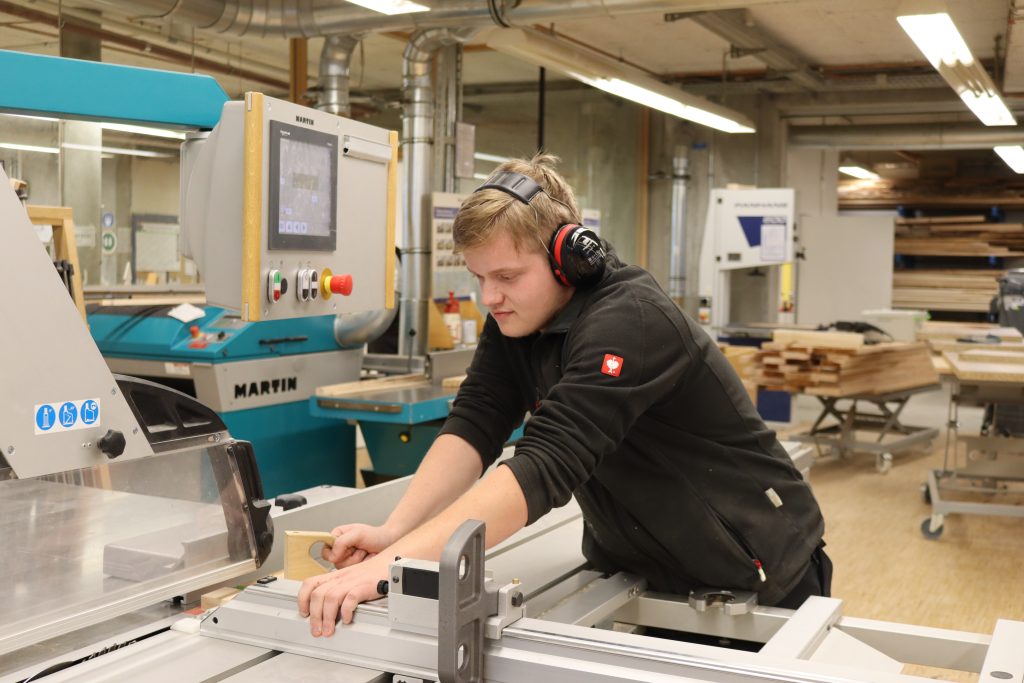 ein junger Mann arbeitet an einer Kreissäge