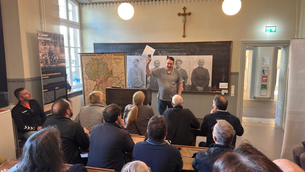 unsere Lehrkräfte sitzen an historischen Schulbänken im Kreismuseum Bitburg-Prüm