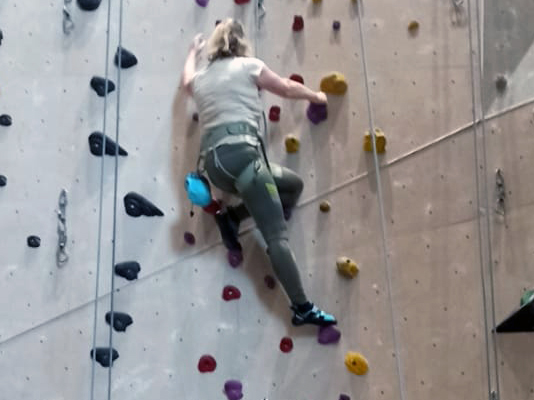 man sieht eine Frau an einer Kletterwand
