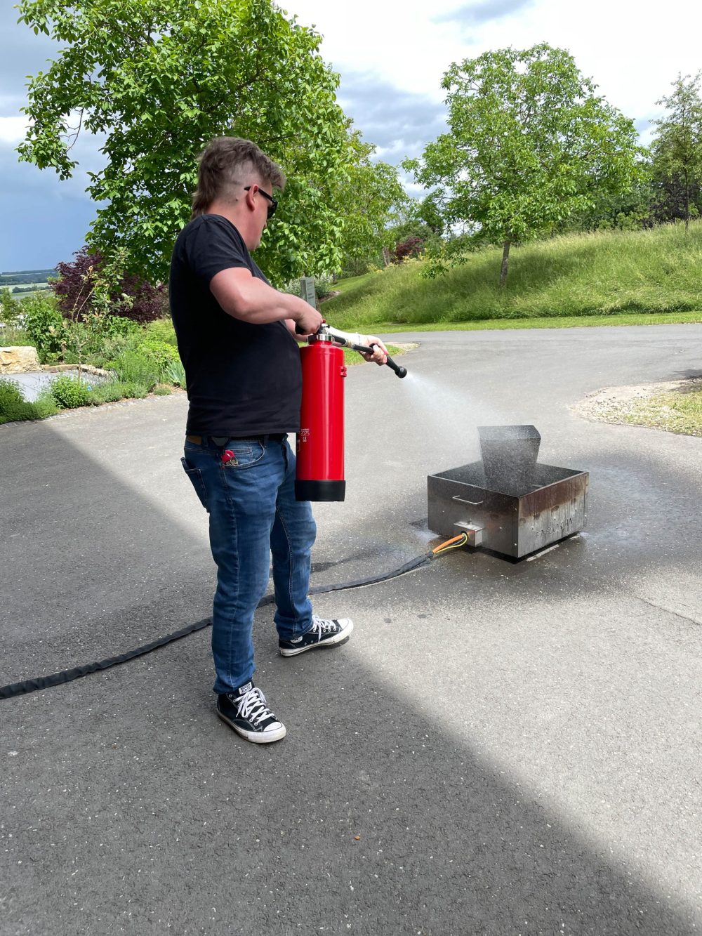 Ein Kollege löscht den Brandsimulator mit einem Feuerlöscher