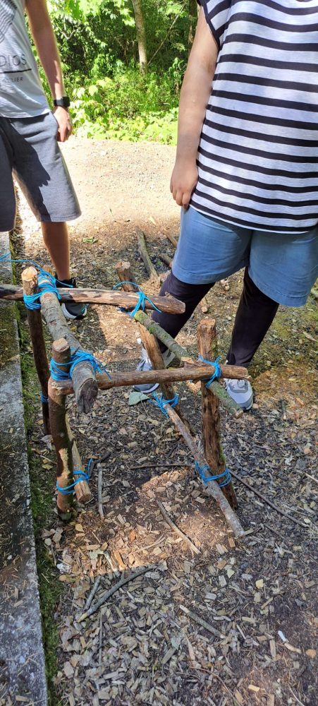 Man sieht einen selbst gebauten Stuhl und zwei Teilnehmende, die zur Hälfte abgebildet sind