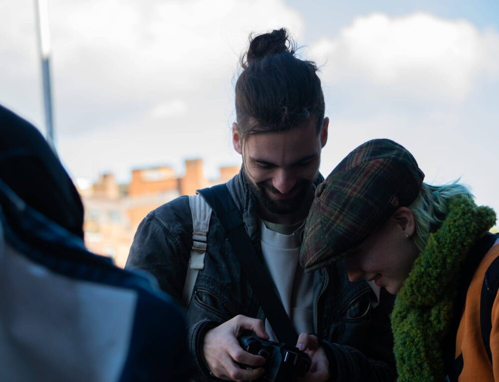 zwei Personen schauen sich Fotos auf einer Kamera an